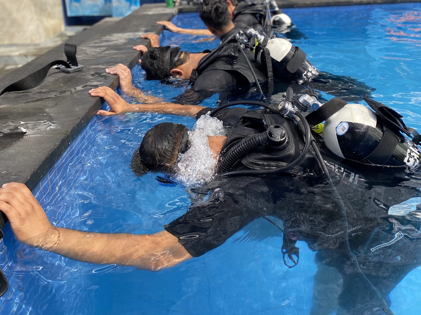 Students practising breathing underwater at the edge of the dive center pool on Gili Trawangan